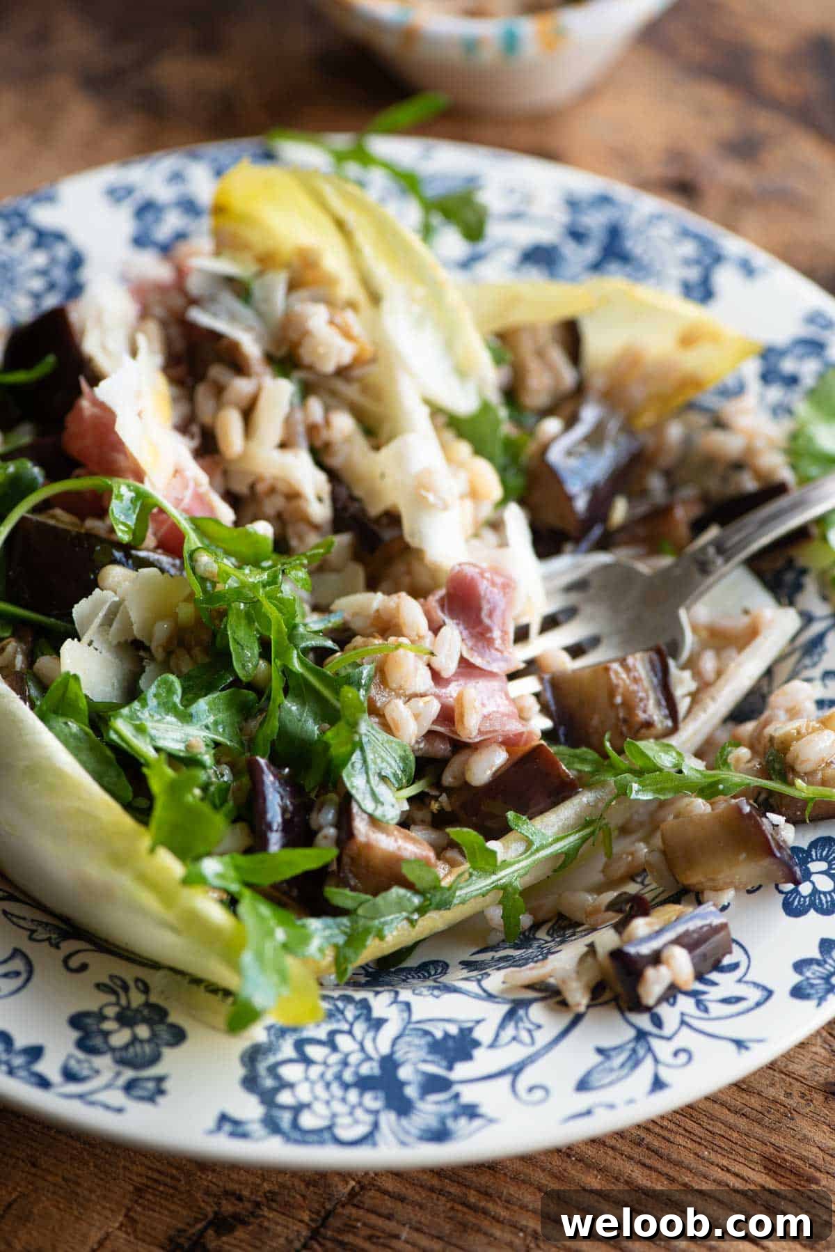 A close up of a eggplant and farro salad made with bitter greens and pine nuts.