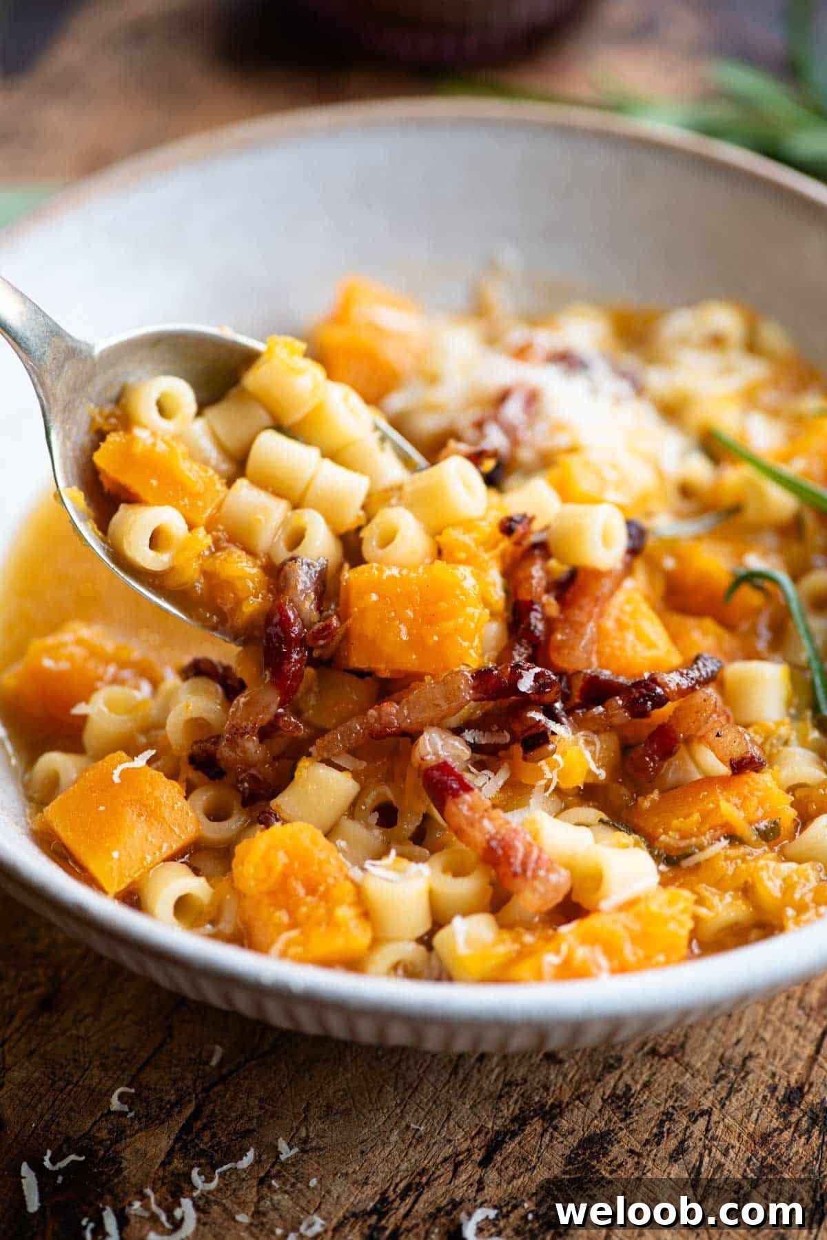 A close up of a spoonful of butternut squash and pasta soup.