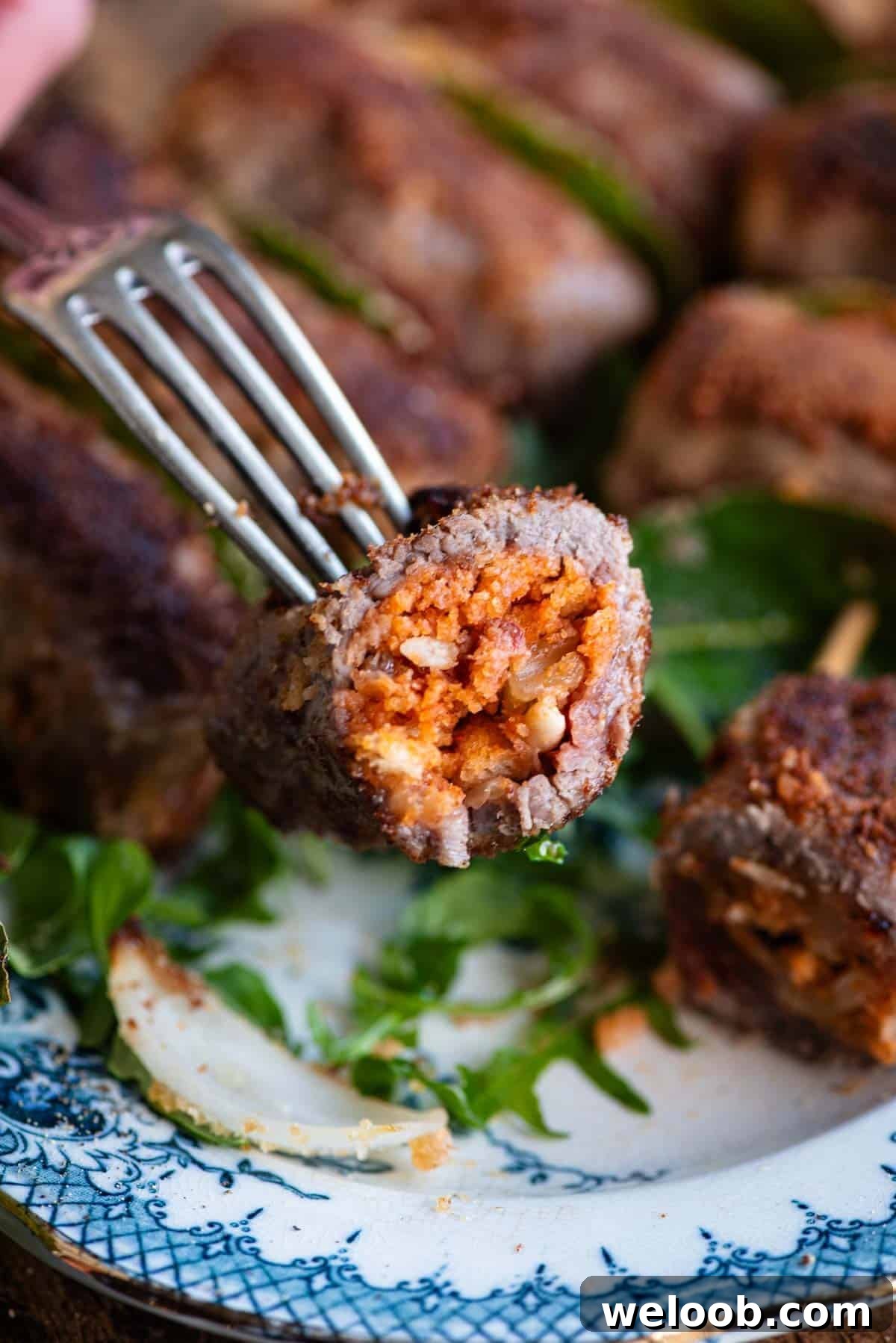 A close up of one Sicilian stuffed beef roll cut in half on a fork.