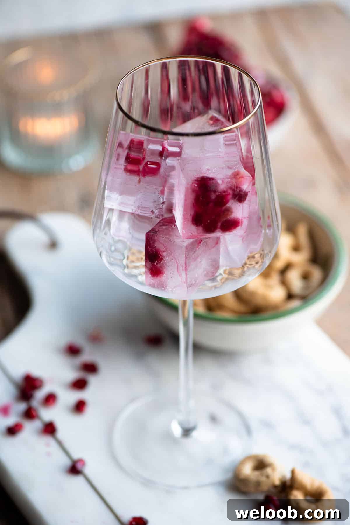 A wine glass with a gold rim filled with pomegranate ice cubes.
