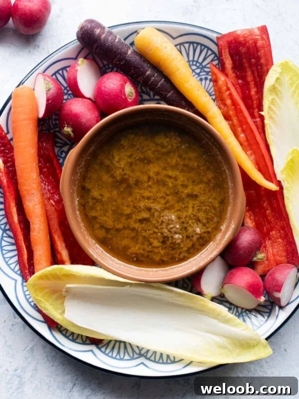 An overhead shot of Bagna Cauda in a terracotta dish with raw vegetables around it.