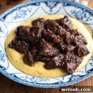 A close up cropped image of Carbonade beef stew on top of polenta.