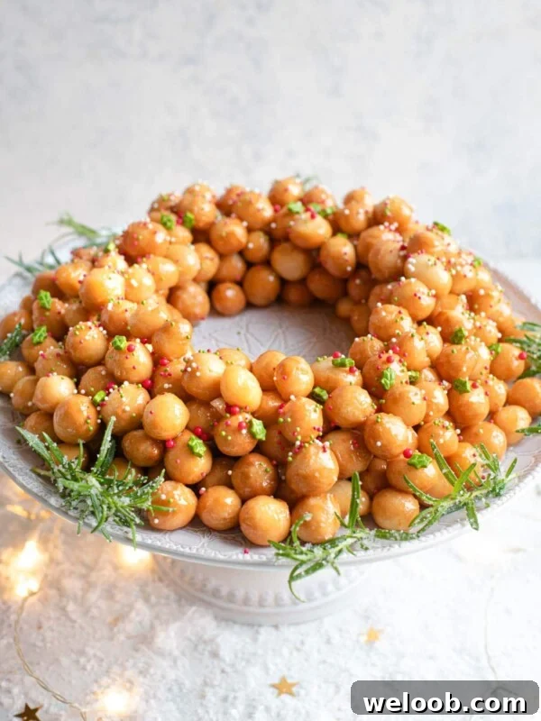 A side shot of Italian struffoli (honey balls) on a cake stand topped with sprinkles