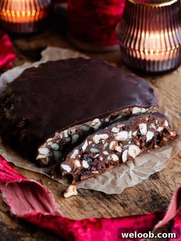 Panpepato cut into slices sitting on a wooden board with christmas red ribbon and candles.