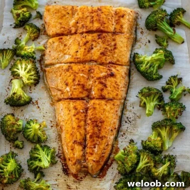 Large salmon fillet and roasted broccoli on a sheet pan