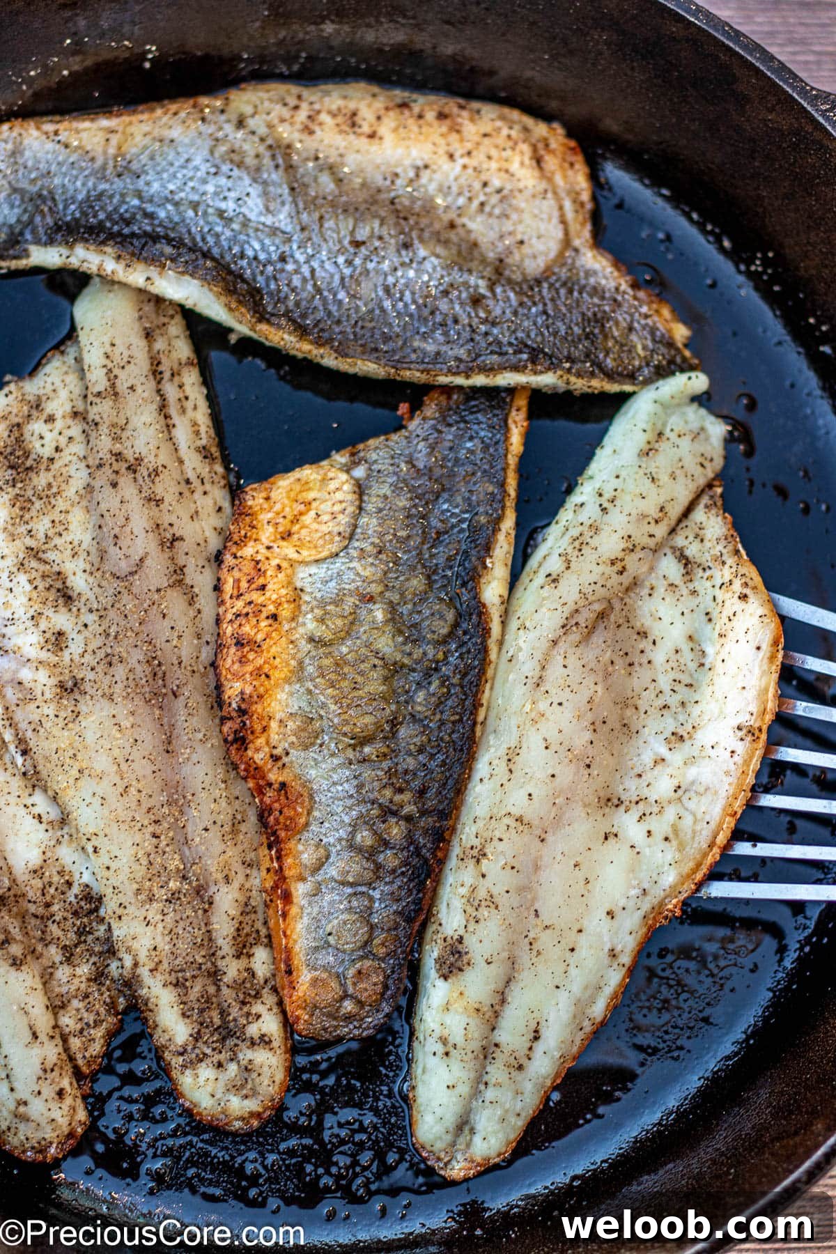Fish spatula flipping cooked sea bass.