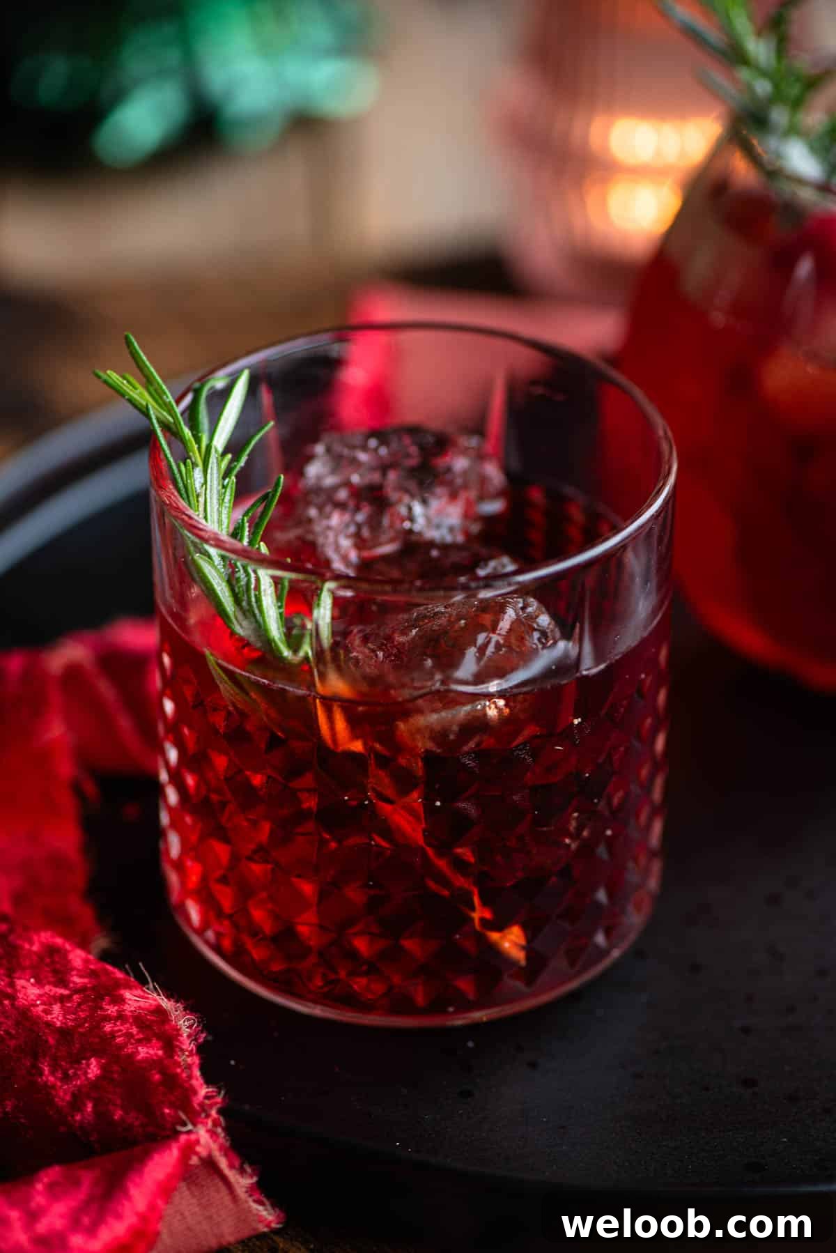 A close up of The Sbagliato Rosso cocktail in a glass with a sprig of rosemary.