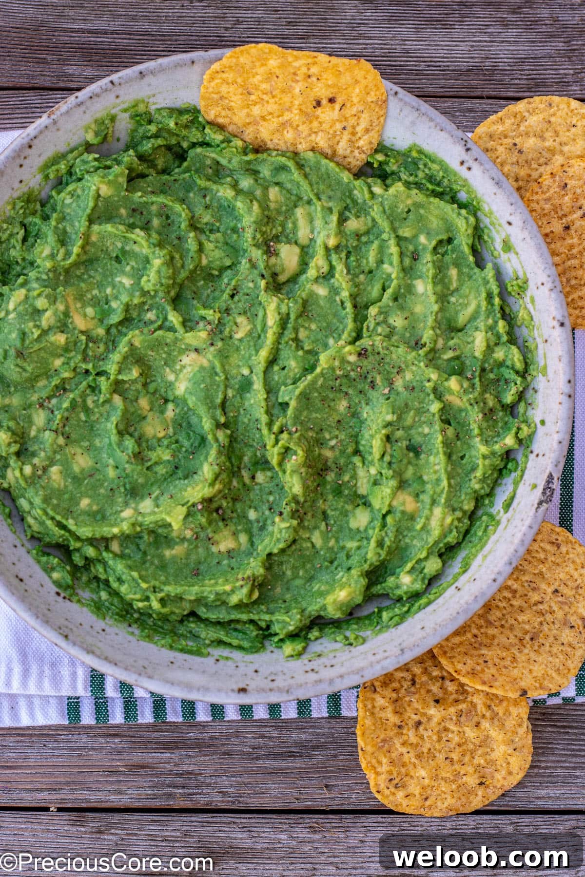 Guacamole in a bowl with a tortilla chip stuck in.