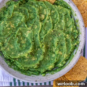 Guacamole in a bowl with a tortilla chip stuck in.