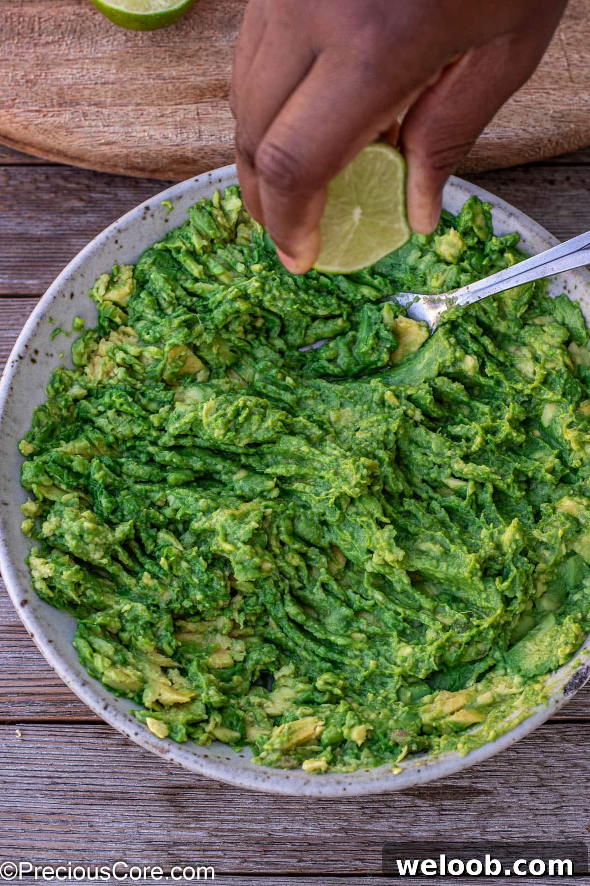 Squeezing lime juice into mashed avocados.