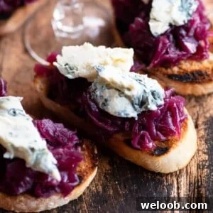 A close up cropped image of red onion crostini topped with gorgonzola cheese.