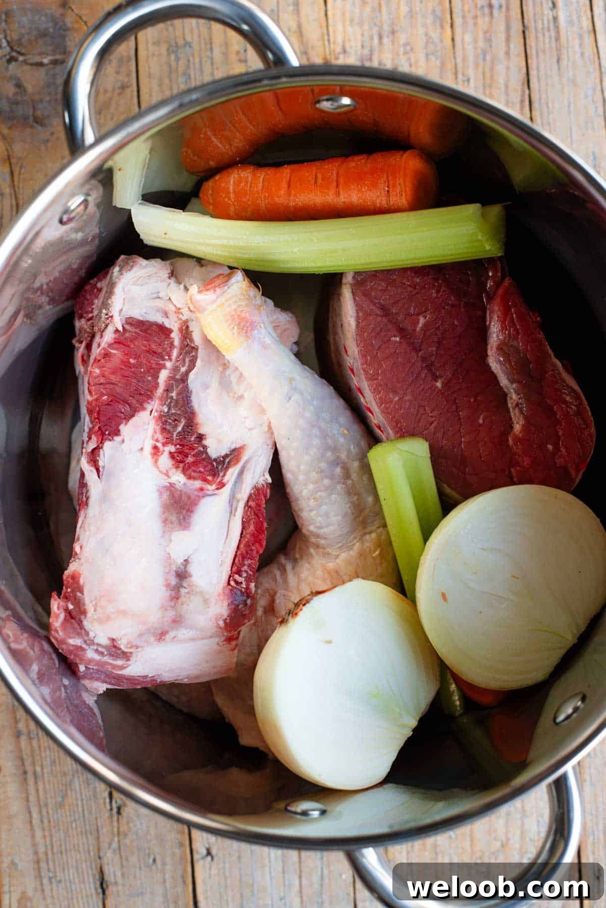 An overhead shot of meat and vegetables in a large stock pot.