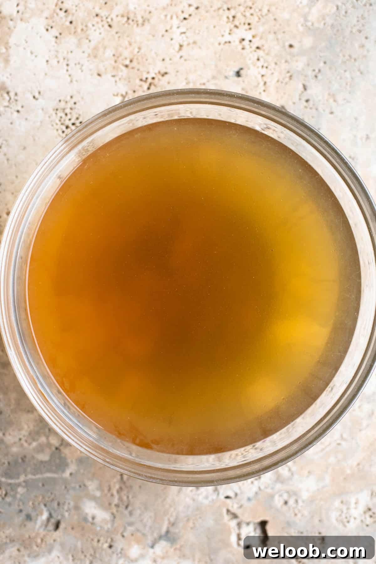 An overhead shot of Italian broth 'brodo di carne' in a glass bowl.