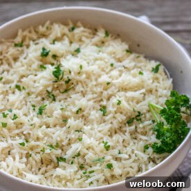 A bowl of garlic herb rice topped with minced fresh parsley.