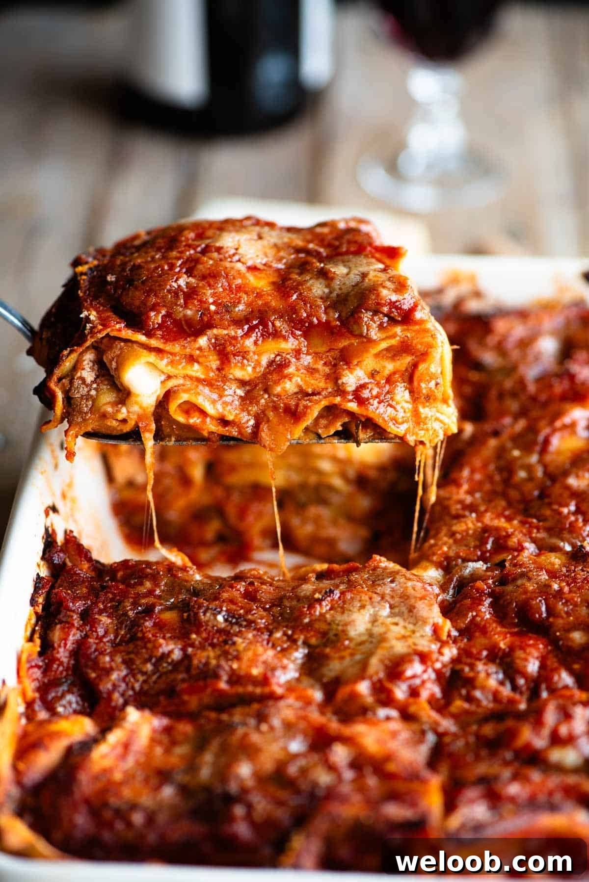A side shot of a slice of neapolitan lasagna getting picked up from a dish.