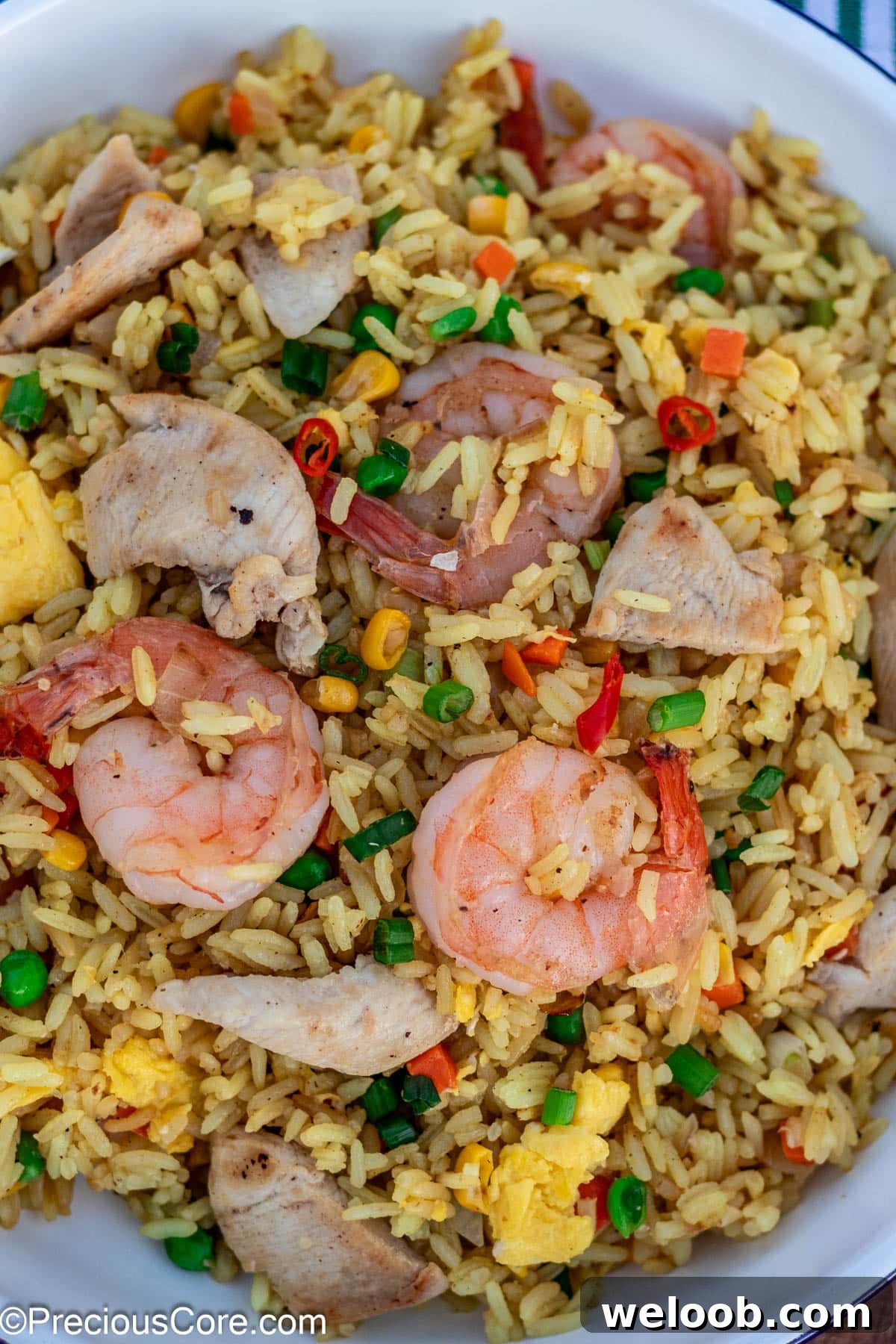 Shrimp and chicken fried rice in a white dish.