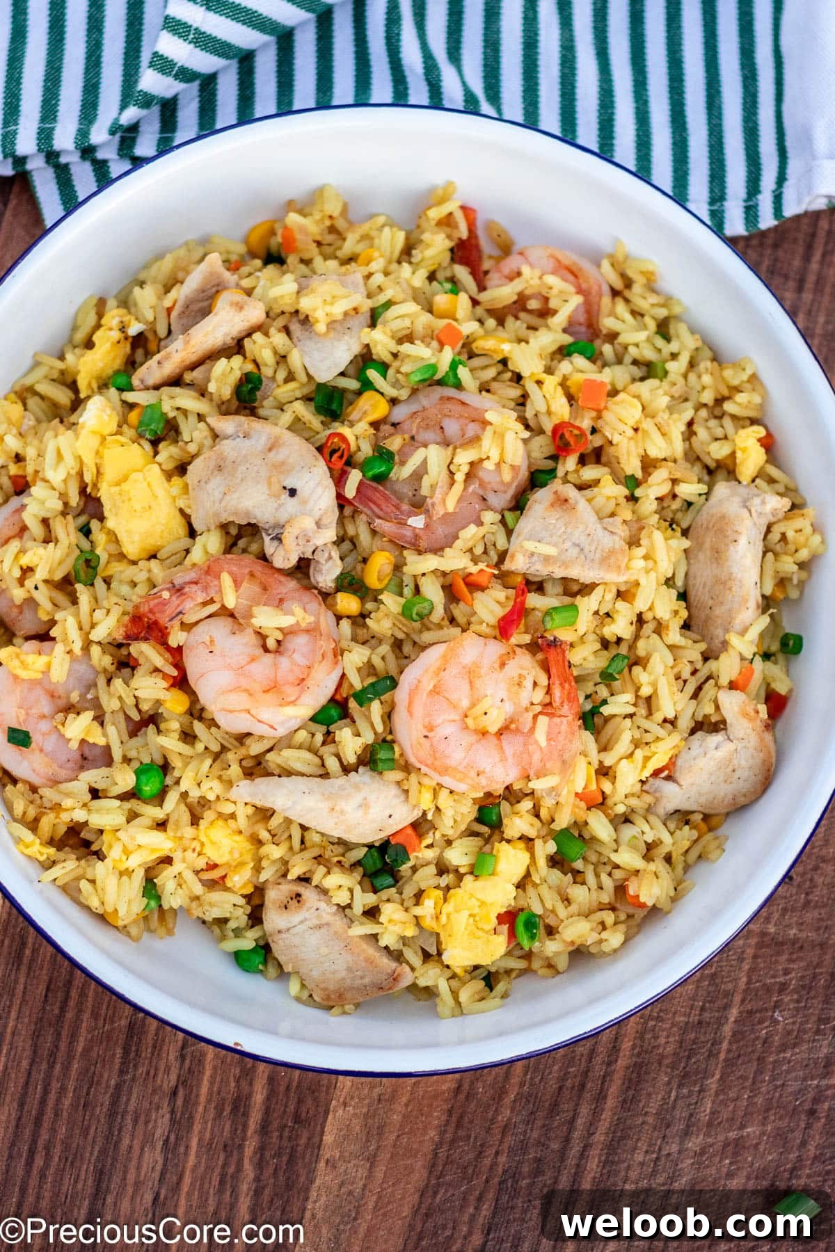 Fried rice in a plate, topped with chicken and shrimp.