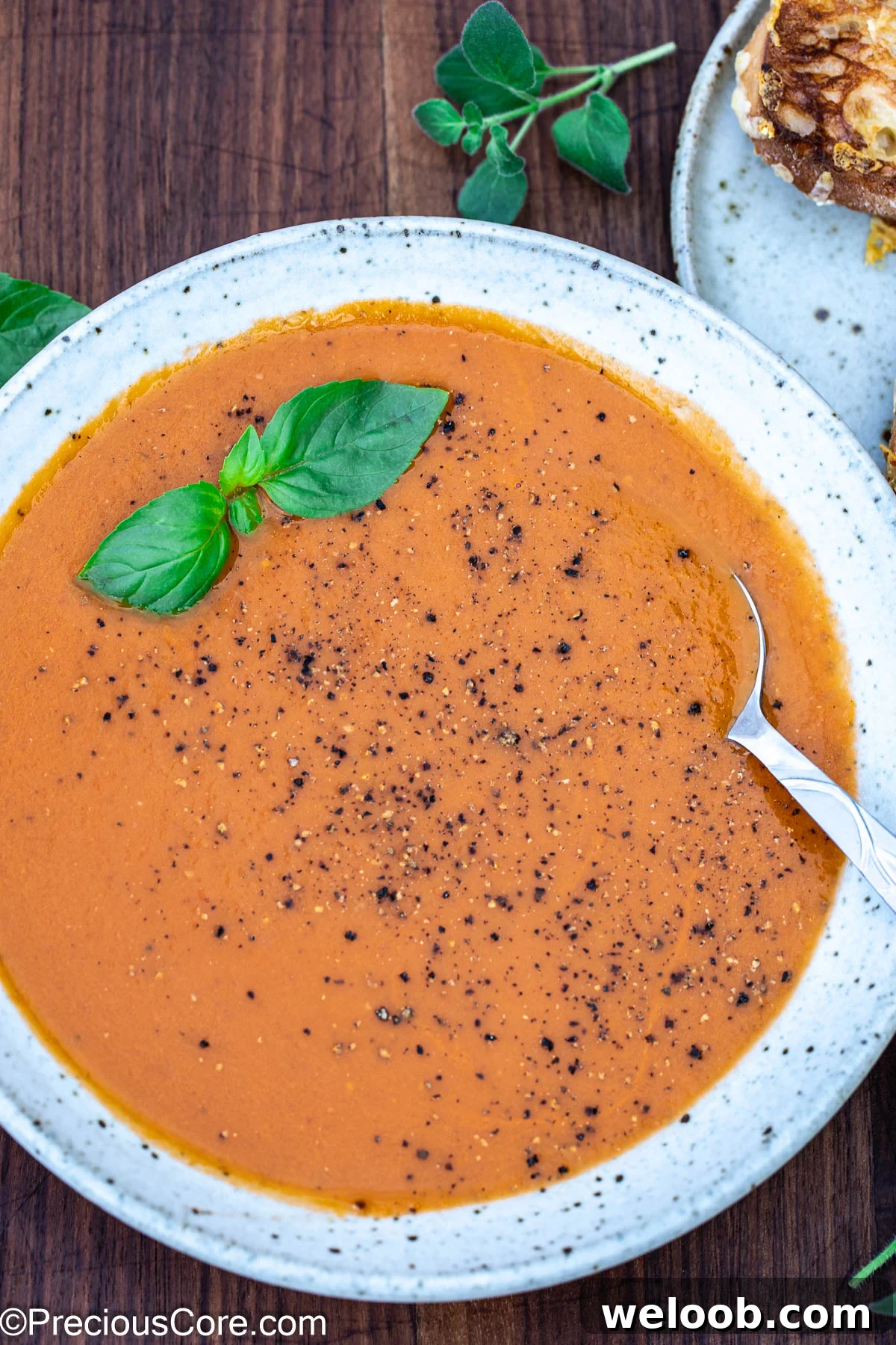 Bowl of tomato soup with black pepper sprinkled on top.