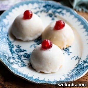 A cropped square image of three Sicilian pastries on a blue plate topped with white icing and a cherry.