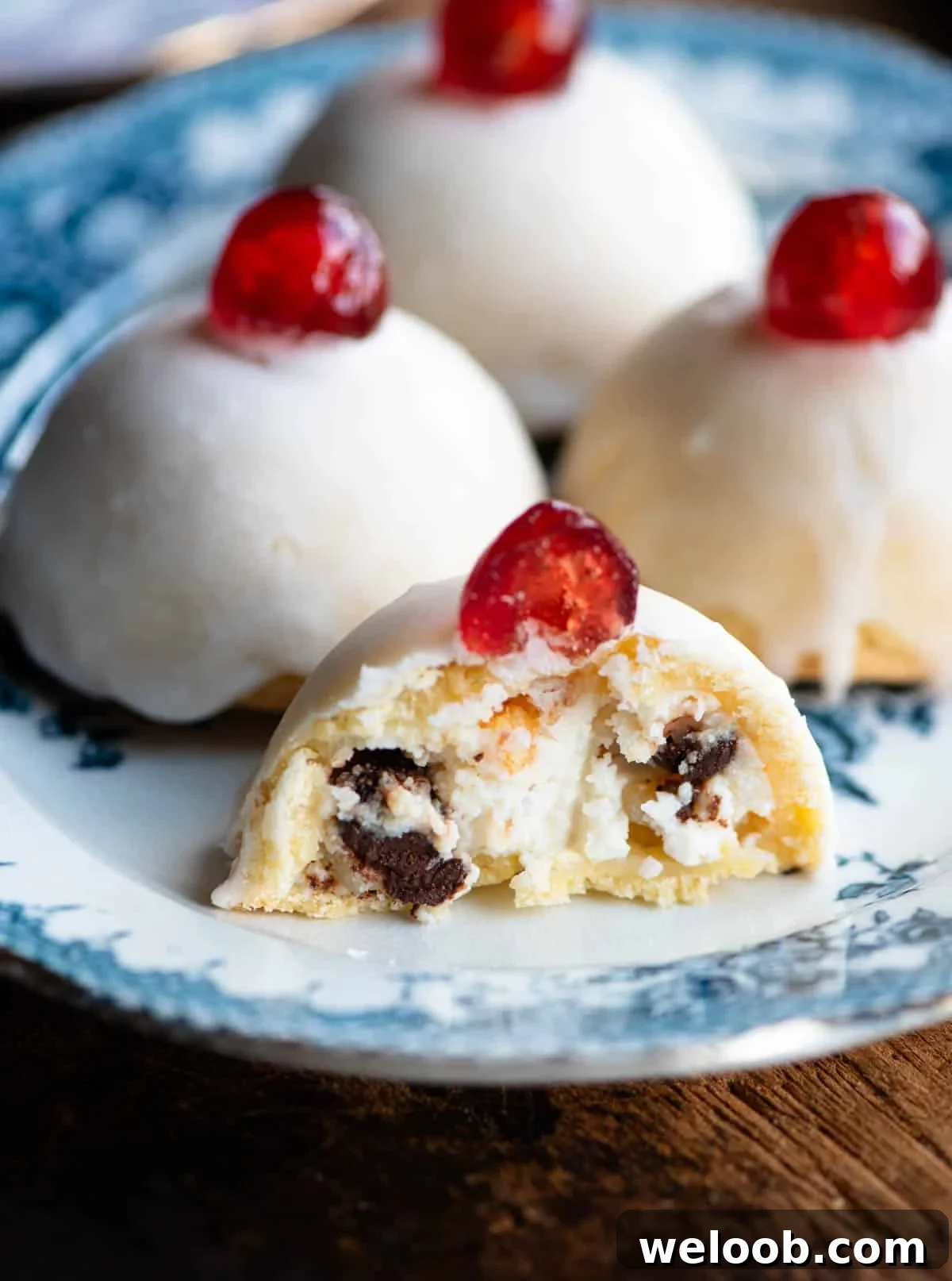 A close up of a Sicilian pastry cut in half showing a ricotta filling with chocolate chips and candied fruit.
