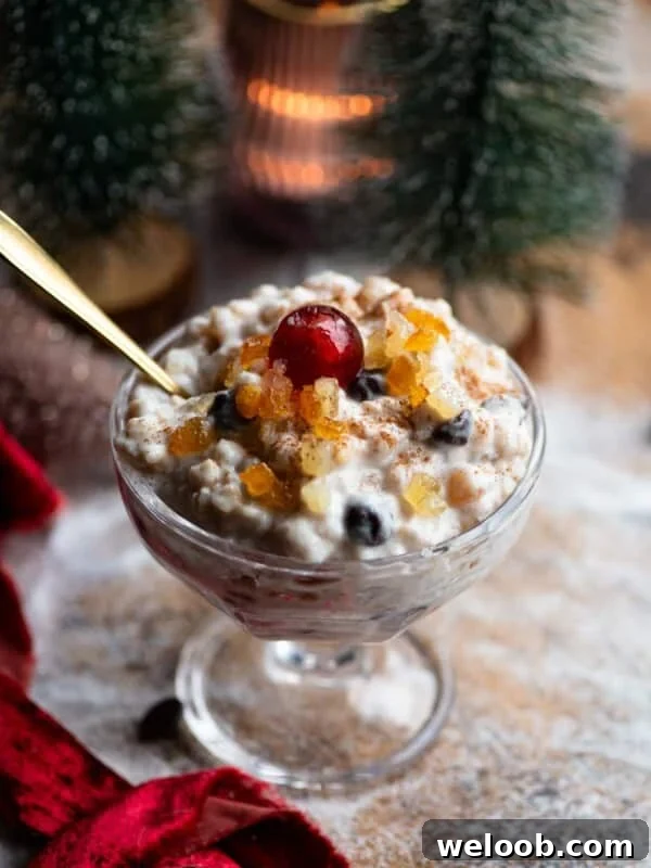 A Sicilian dessert made with ricotta, grain and candied fruit in a glass serving dish topped with a candied cherry.