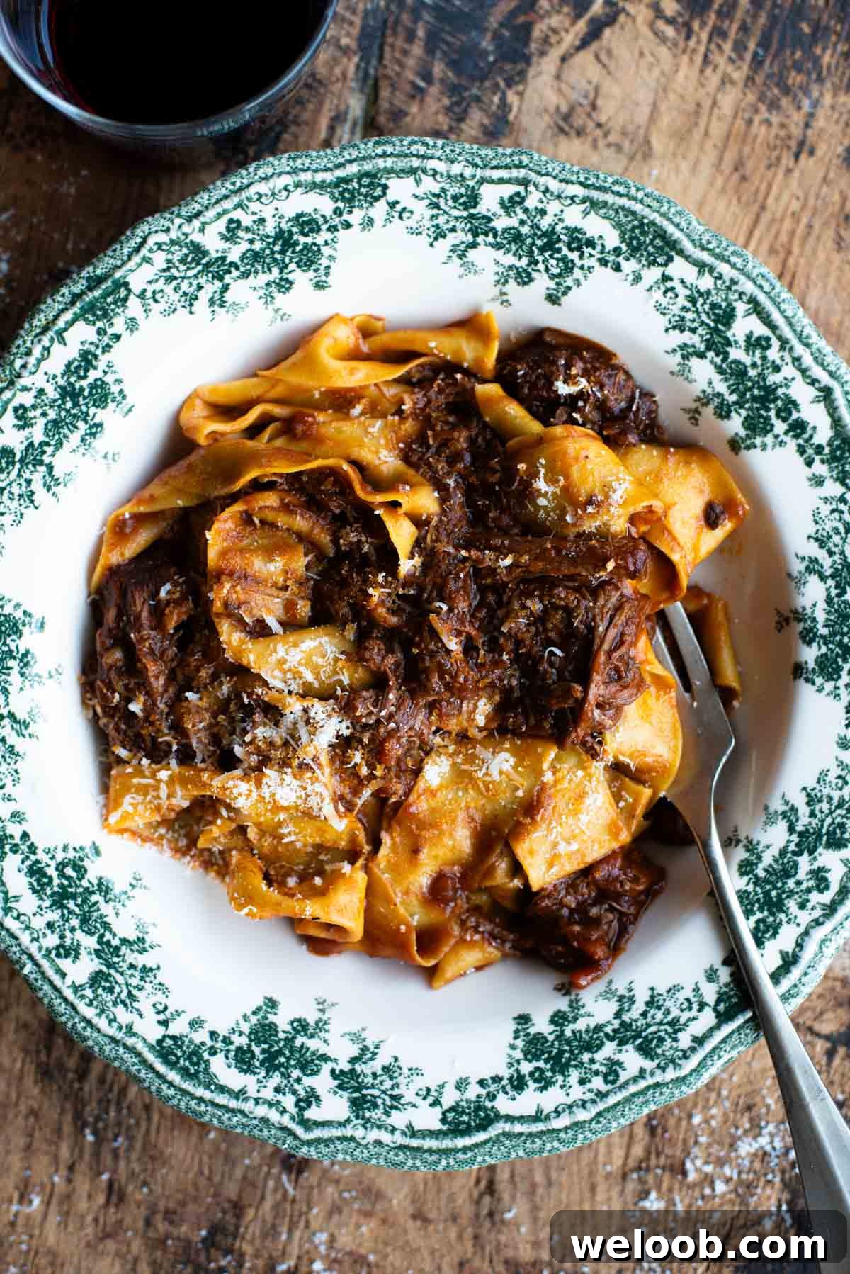 An overhead shot of a short rib beef ragu in a green and white bowl.