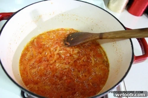 Poulet DG Recipe: How to Make Cameroon’s Classic Chicken Dish 12 Wooden spoon stirring a pan with tomatoes.