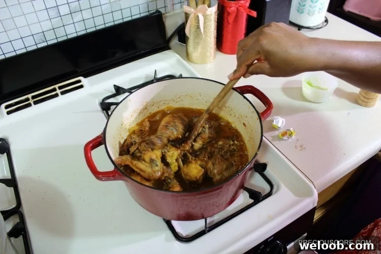 Poulet DG Recipe: How to Make Cameroon’s Classic Chicken Dish 13 Person stirring a Dutch oven of chicken.