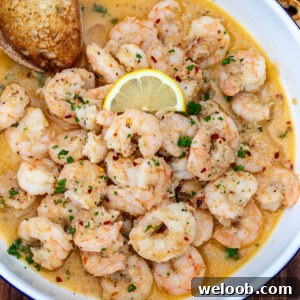 Crusty bread in a bowl of shrimp in white wine sauce.
