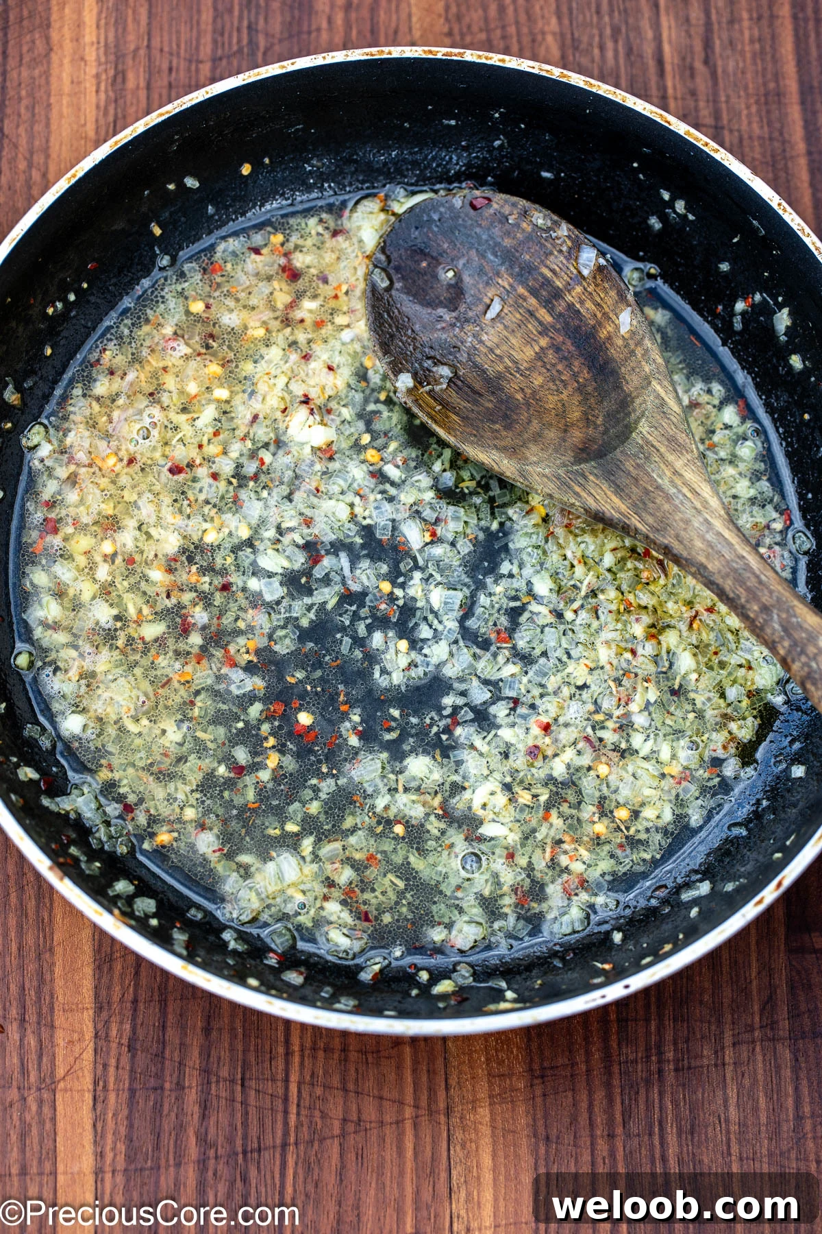 White wine sauce with garlic and shallots in a skillet.