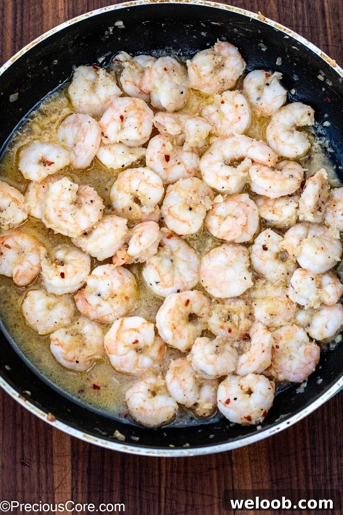 Cooked shrimp in a skillet with white wine sauce.