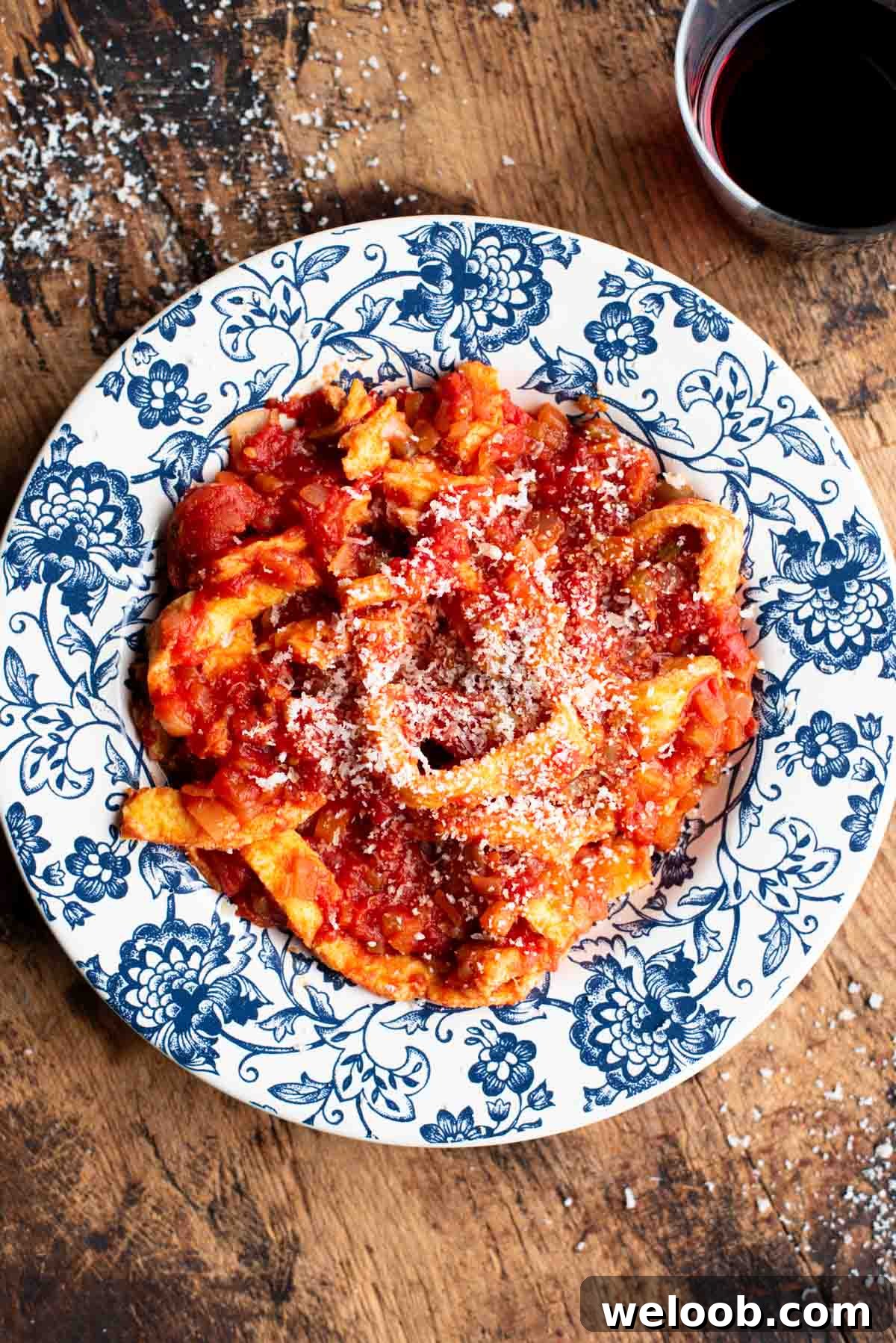 Trippa Finta (Italian omelette in tomato sauce) in a blue and white bowl sitting on a wooden surface.
