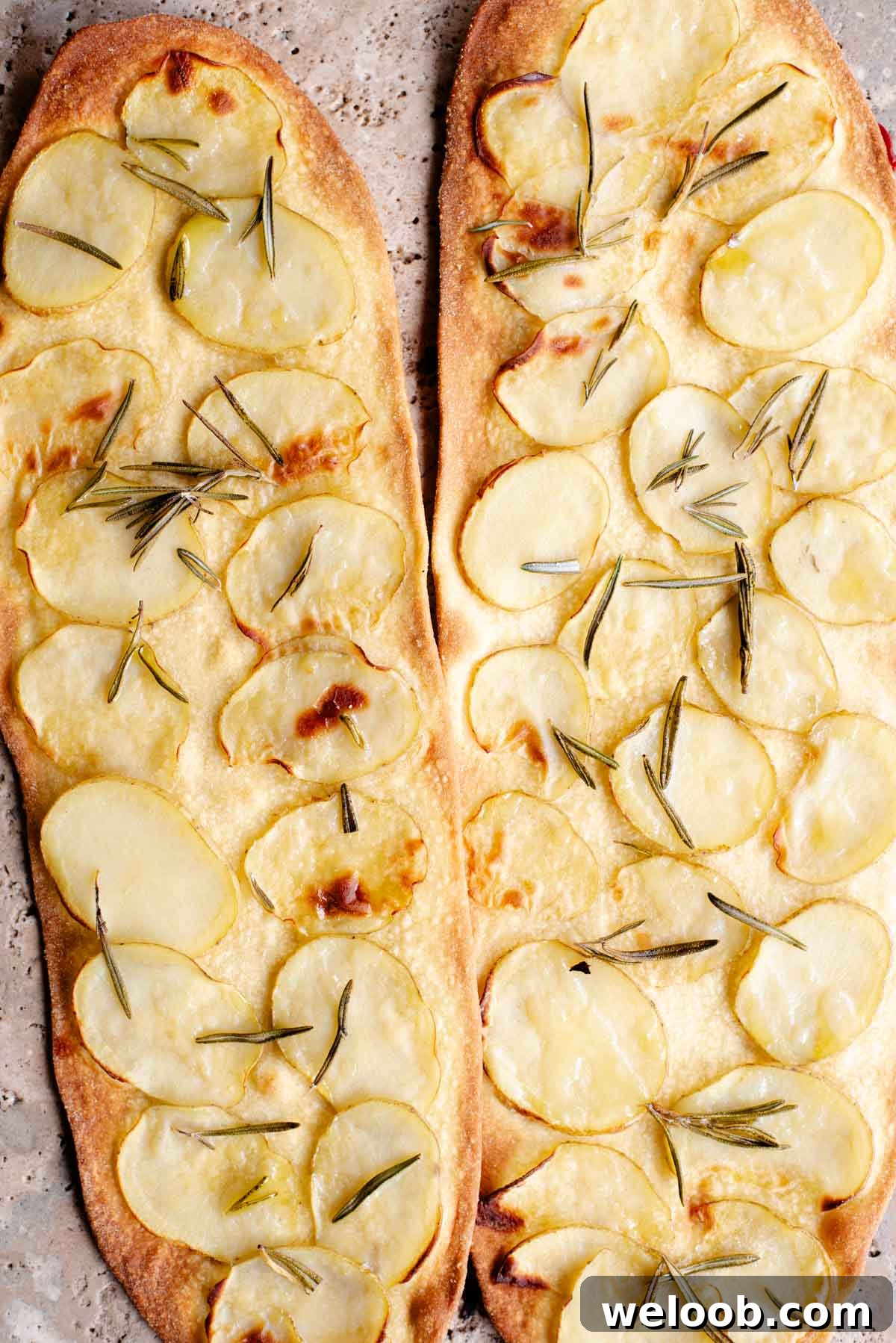 Two long and thin pizzas with slices of potato and rosemary on top.