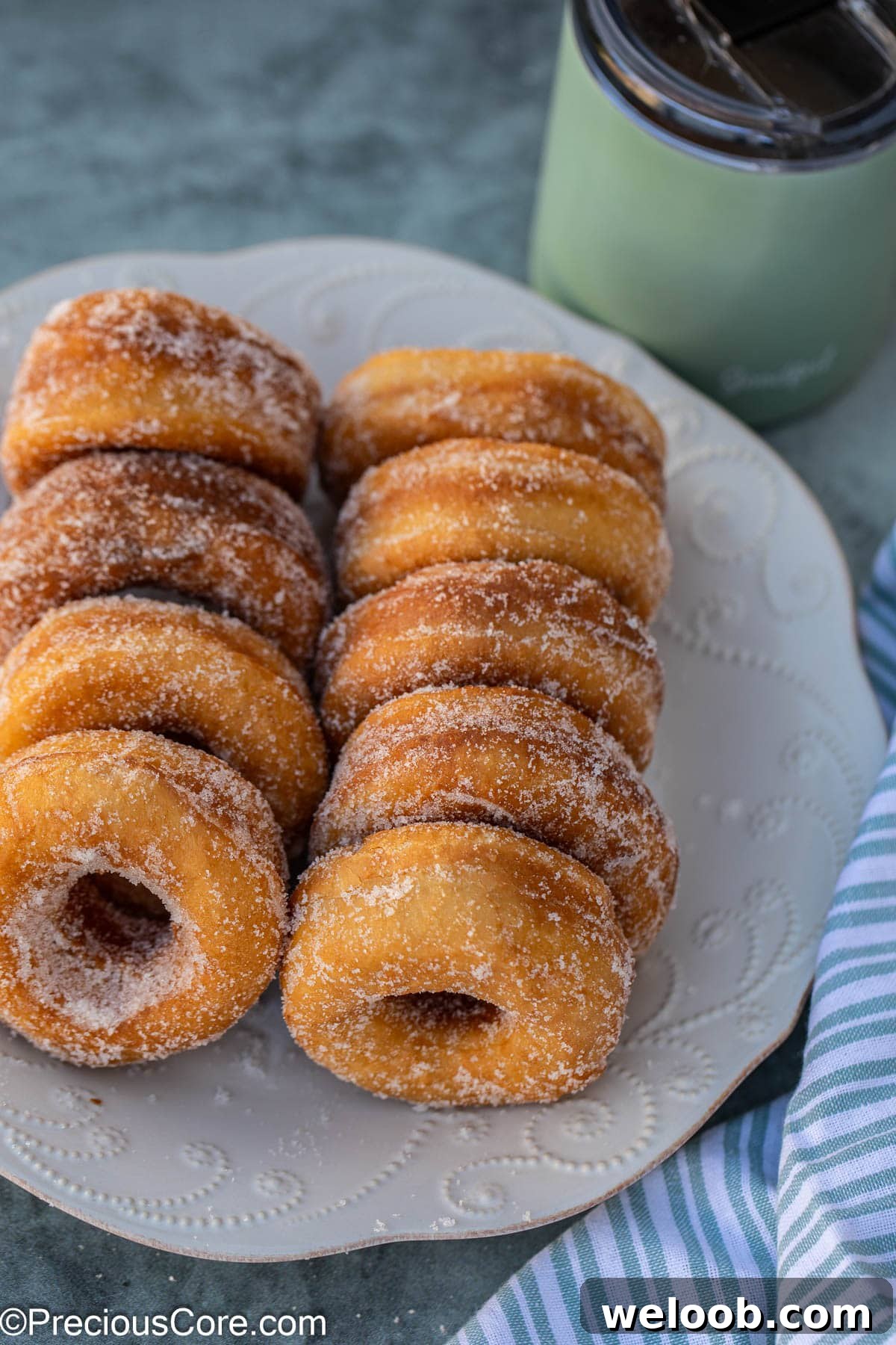 Nine sugar coated donuts on a white plate.