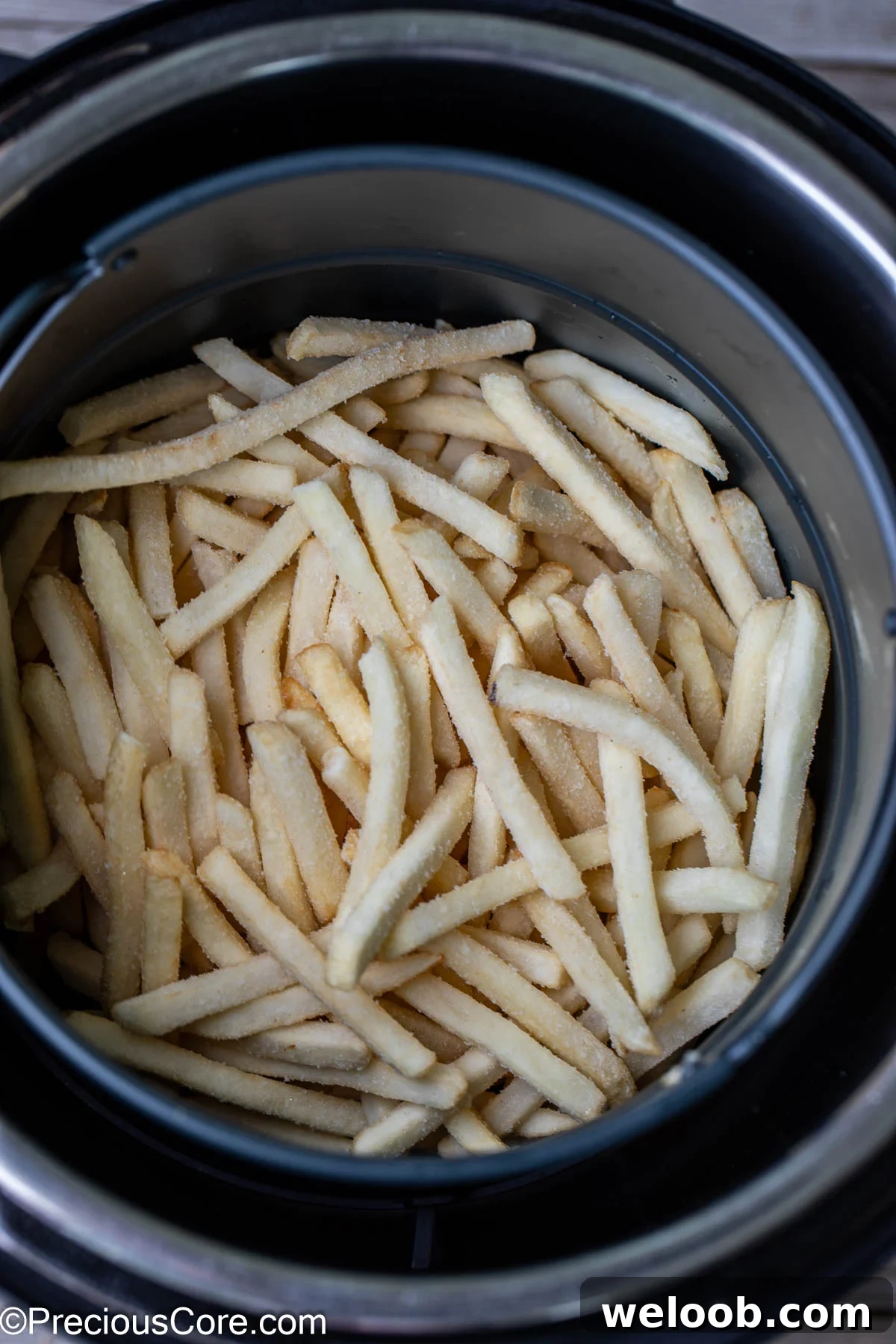 Frozen fries in a round air fryer basket.