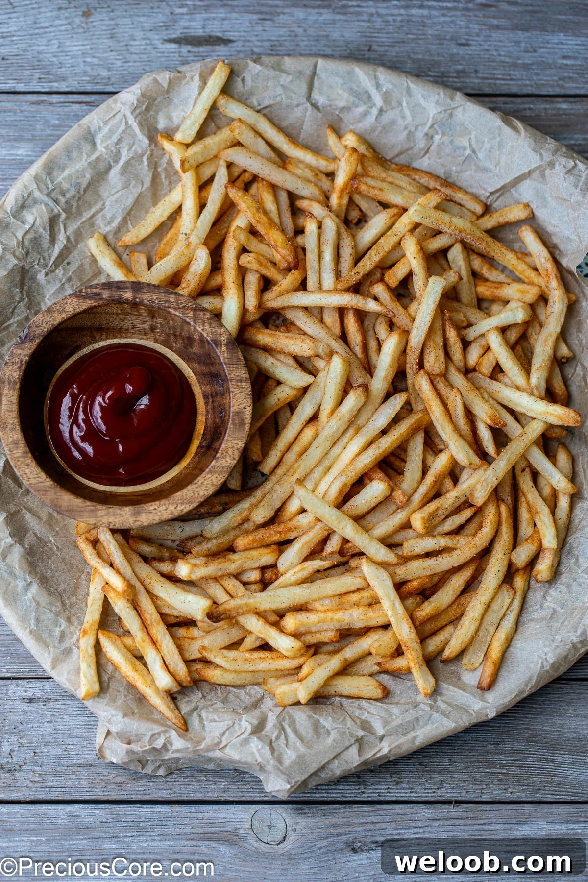 Fries on a round serving platter with a bowl of ketchup nearby.