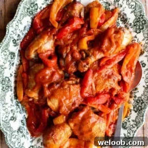 A close up of chicken and peppers on a green and white servings plate.
