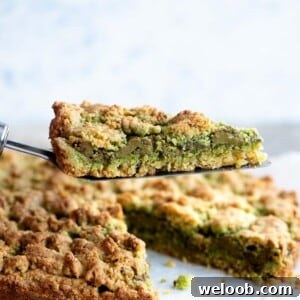 A close cup of a slice of pistachio crumb cake being help up on a cake server.