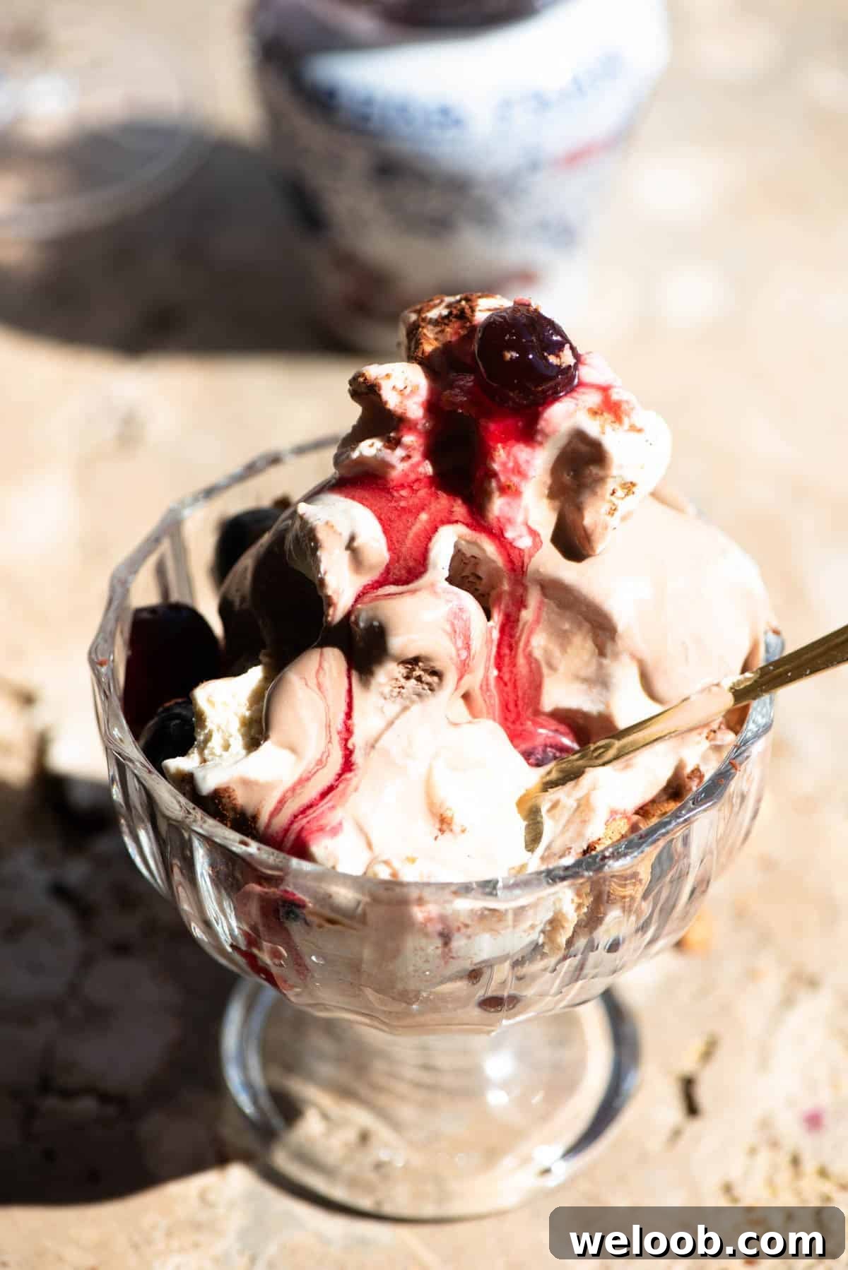 A close up of an Italian ice cream sundae melting in a glass bowl with a amarena cherries.