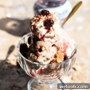 A close up of an Italian ice cream sundae in a glass jar topped with whipped cream and amarena cherries.