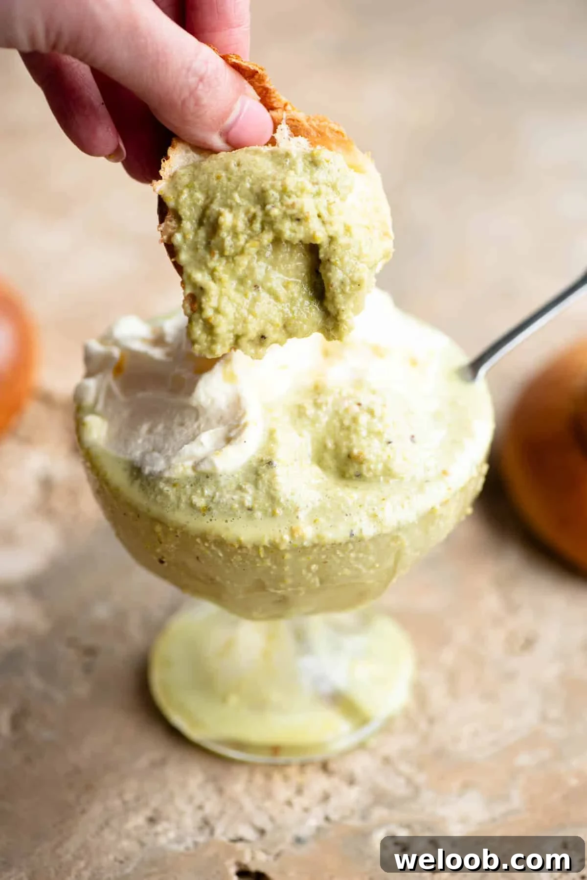 A piece of brioche being dunked into pistachio granita.