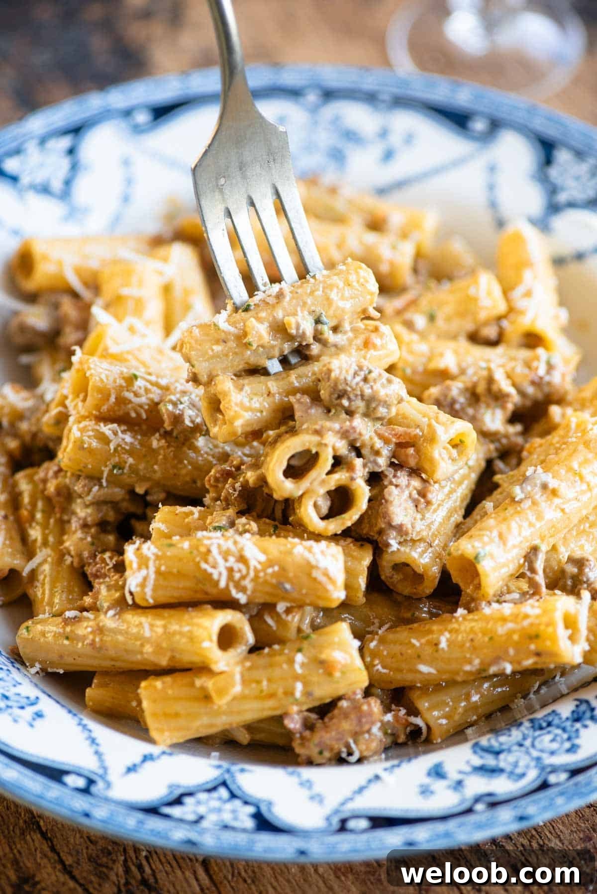 A close up of a fork picking up a bite of pasta in a creamy meat sauce.