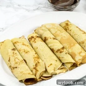 Cameroonian pancakes rolled on a white plate.