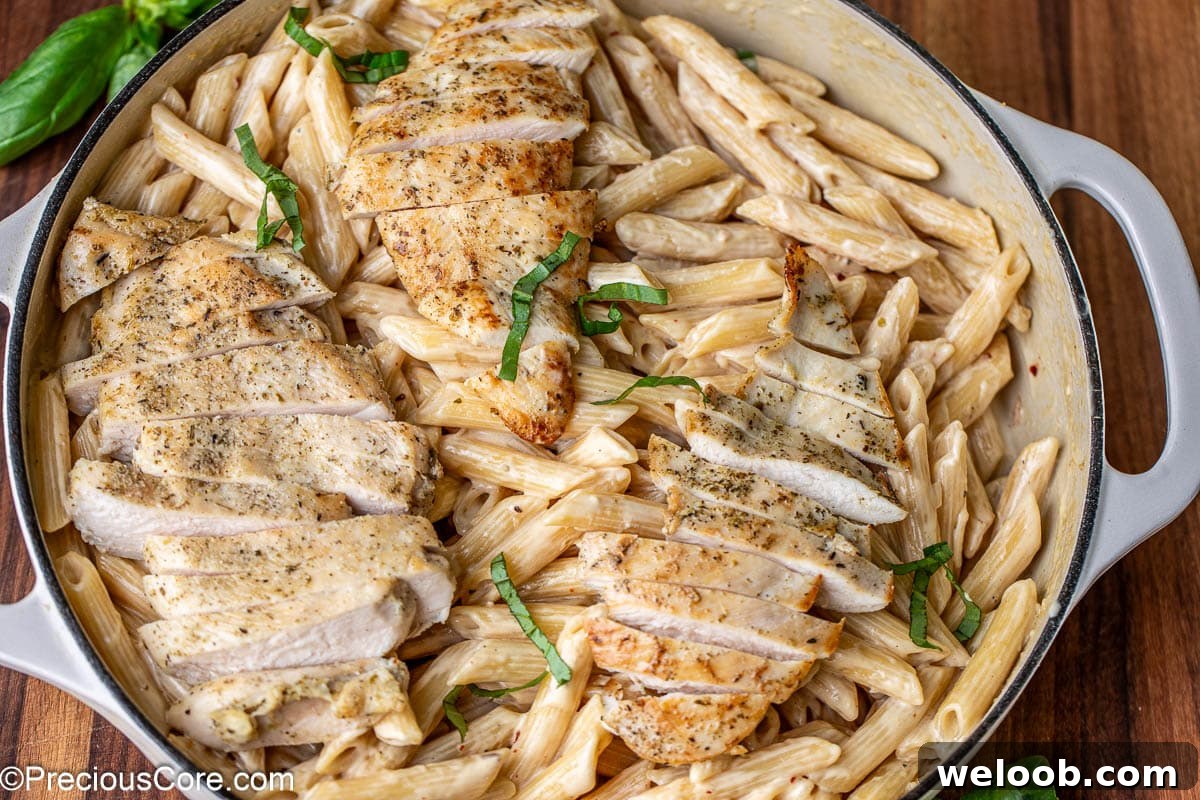 Landscape image of garlic parmesan creamy pasta topped with chicken.
