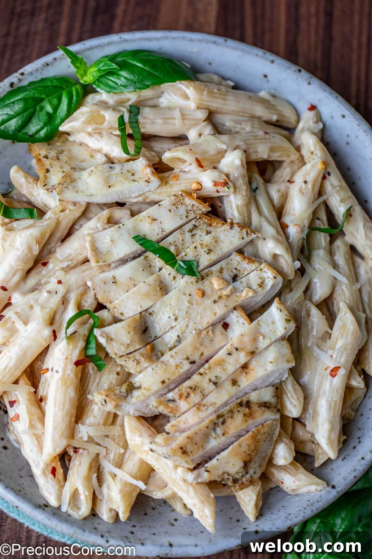 A bowl of creamy pasta topped with sliced chicken breast.