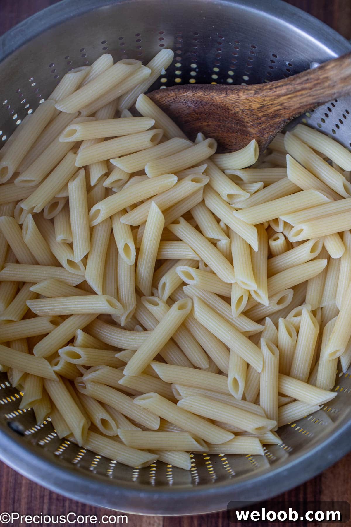 Drained cooked pasta in a stainless steel colander.