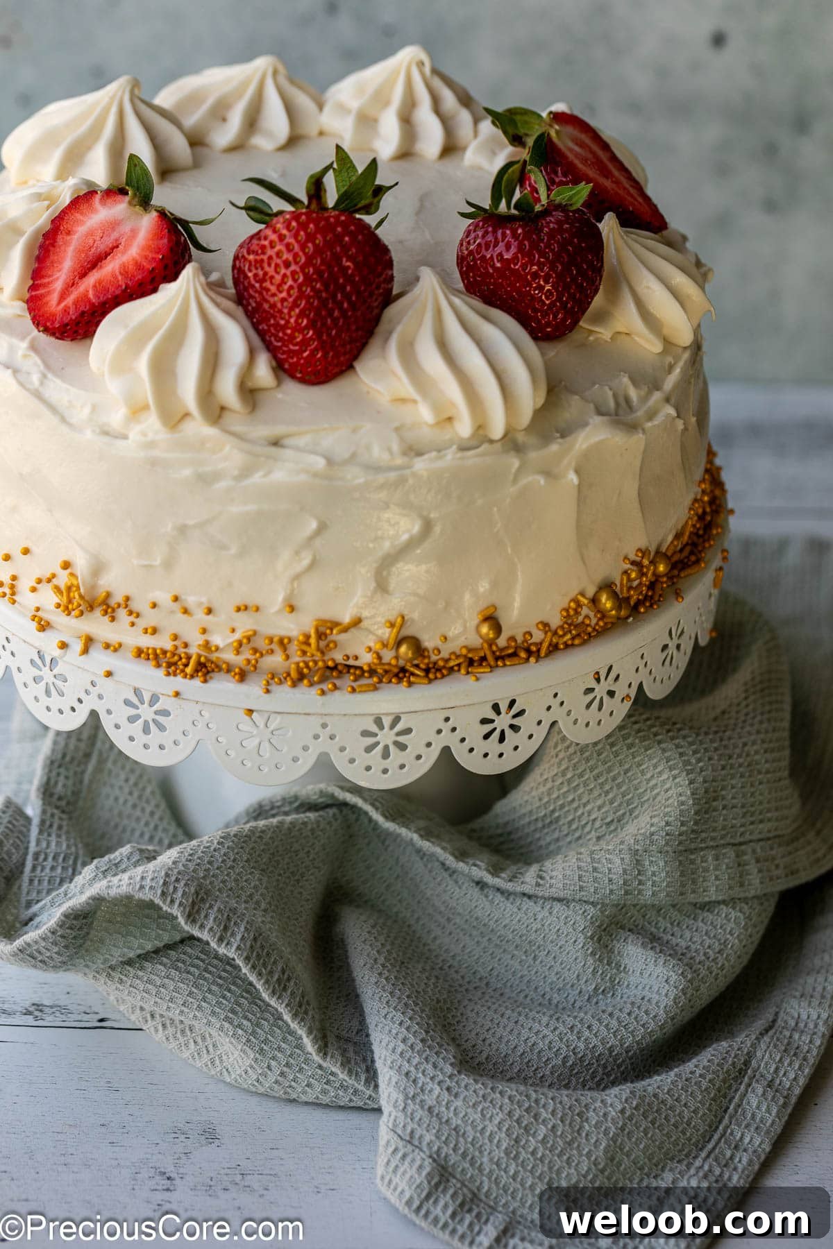 Cake covered in cream cheese frosting on a cake stand.