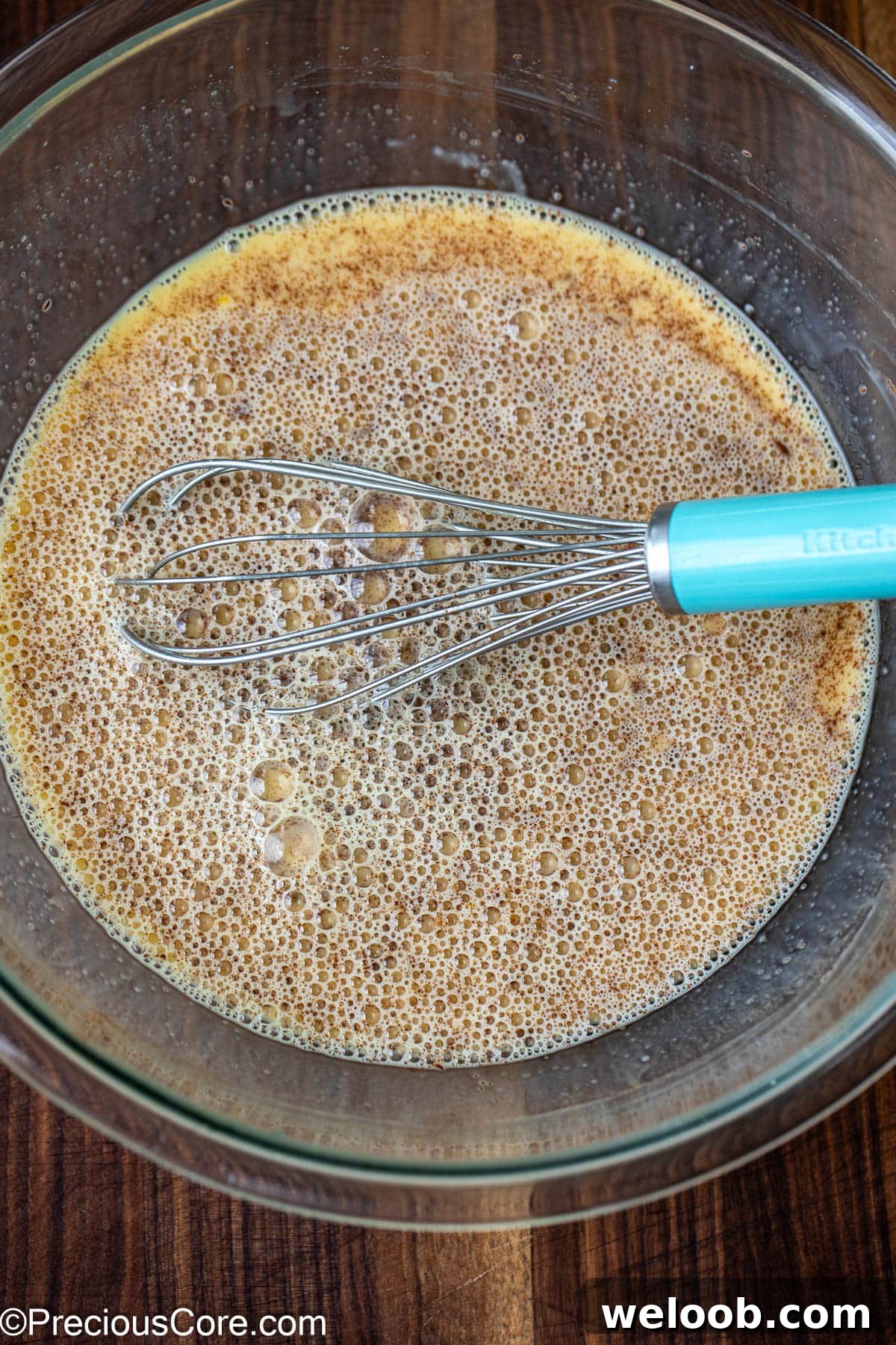 Eggs and milk mixture in a large bowl with a whisk.