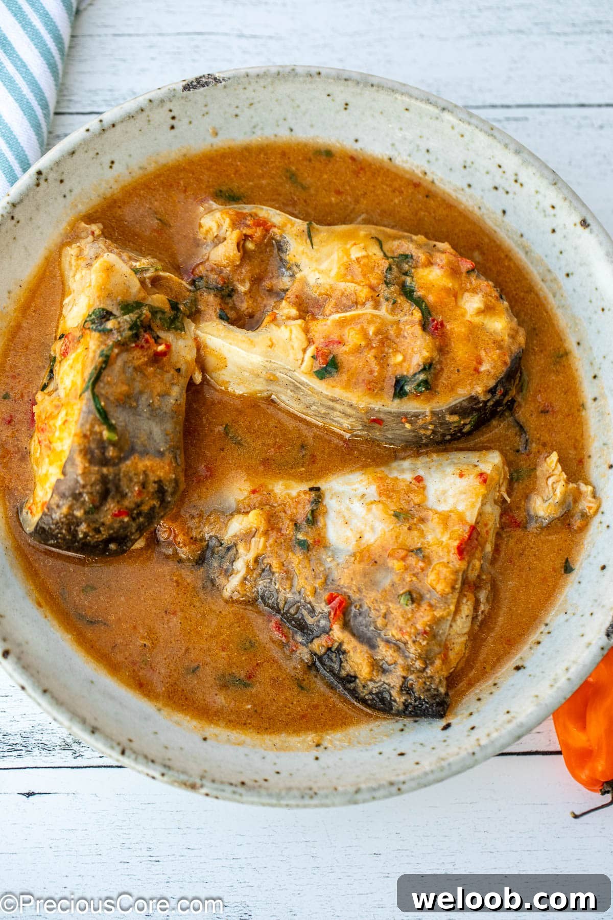 A bowl with three steaks of catfish in pepper soup.