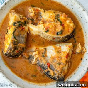 A bowl with three steaks of catfish in pepper soup.